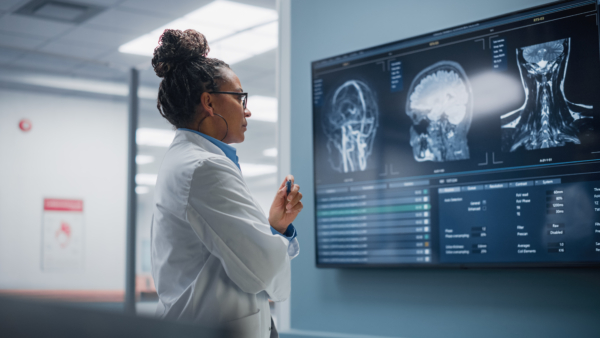 Black Female Neurologist, Neuroscientist, Neurosurgeon, Looks at TV Screen with MRI Scan with Brain Images